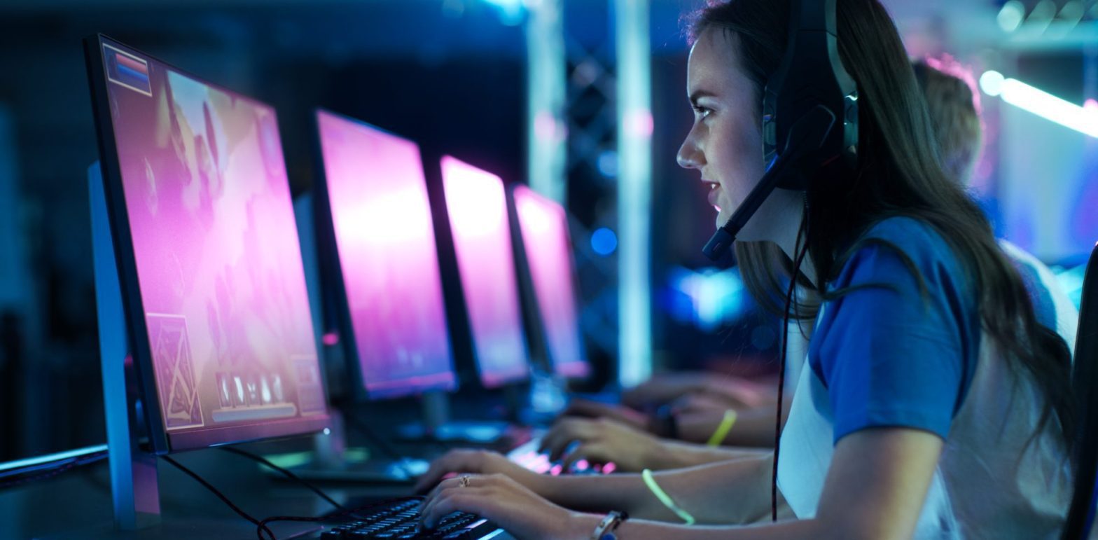 In a dimly lit room, a person wearing a headset is intensely focused on the computer screen, preparing for the upcoming Corte Madera Esports Tournament.