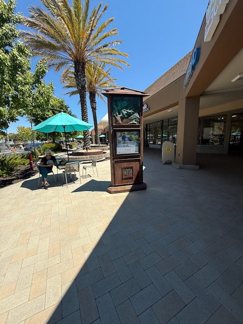 Umbrella covered patio tables near DubDub AI Arcade at Bon Air Center