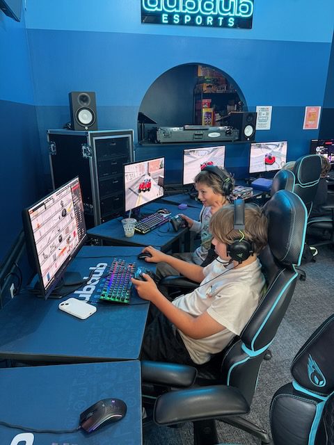 Friends playing side by side at DubDub AI Arcade gaming stations