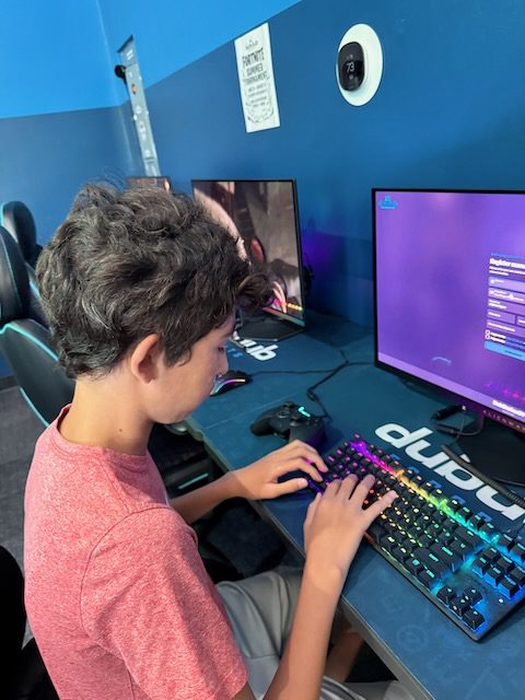 Young player using a keyboard at a DubDub AI Arcade gaming station