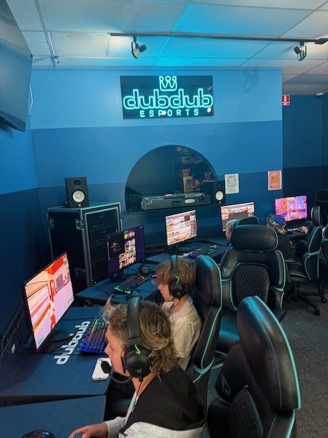 Young players wearing headsets at DubDub AI Arcade gaming stations