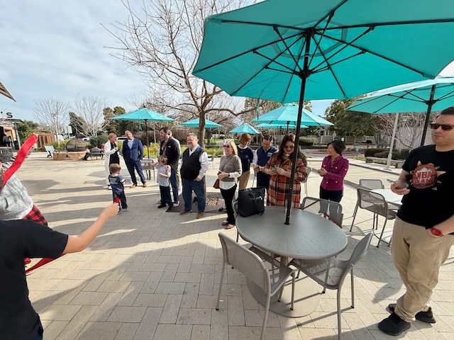 Guests outside DubDub AI Arcade under patio umbrellas at Bon Air Center