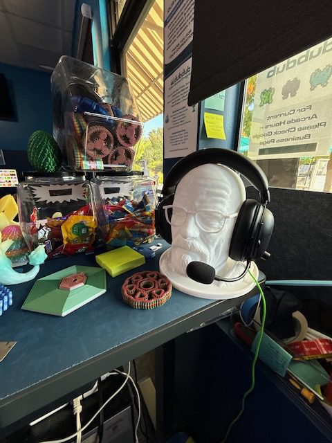DubDub AI Arcade products, plush items, and headphones near a window