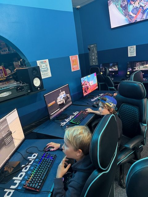 Young players at side-row gaming stations inside DubDub AI Arcade