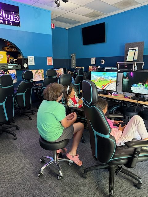 Players at DubDub AI Arcade stations with staff nearby in the gaming room
