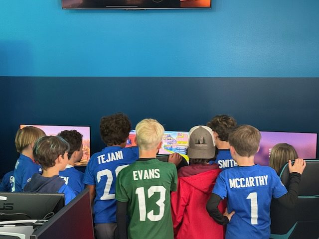 A group of young players standing together at DubDub AI Arcade gaming stations